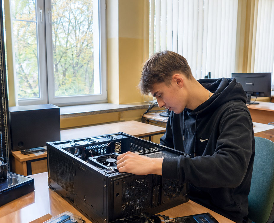 Uczeń technika informatyka podczas składania komputera