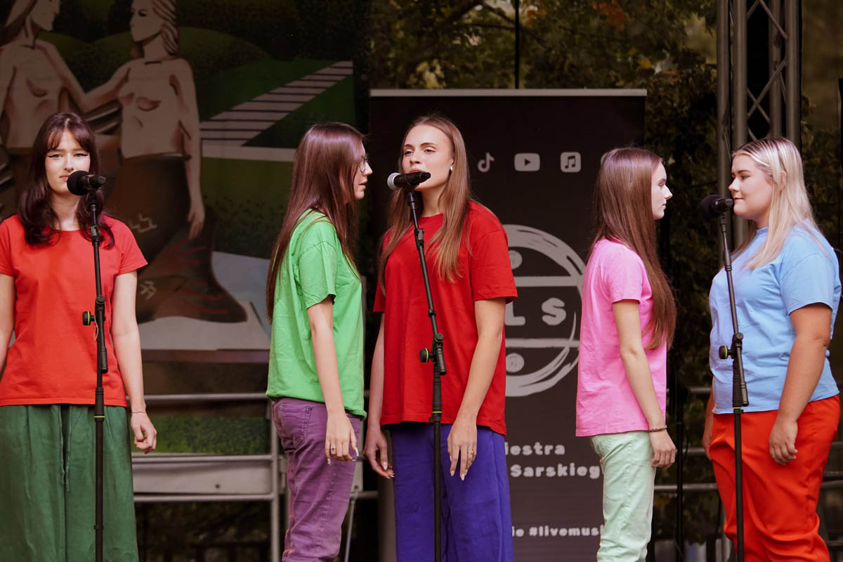 Uczestniczki Teatru NORA ZSŁ w kolorowych strojach podczas występu na scenie Dzielnicowego Pikniku Rodzinnego.