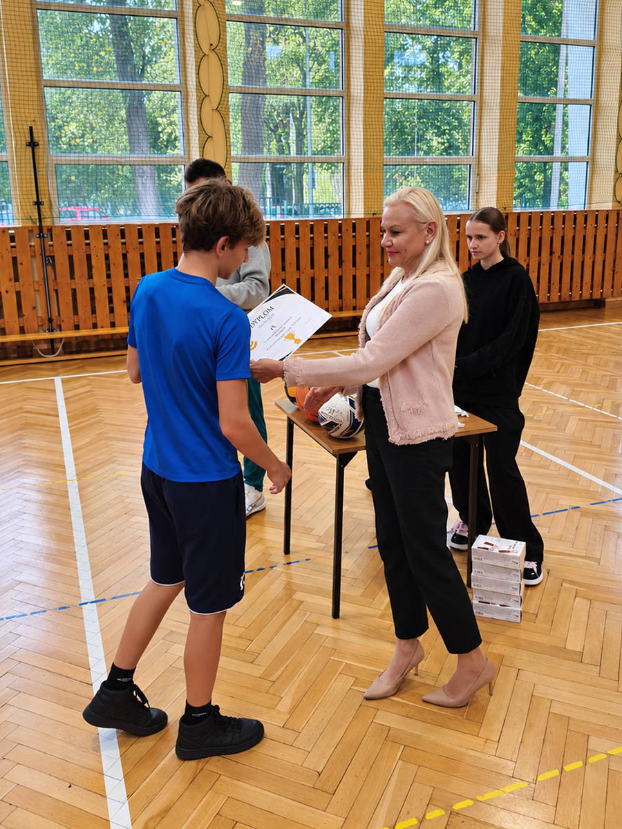 Pani dyrektor Alicja Wodecka wręcza dyplom i nagrodę uczestnikowi zawodów sportowych Pierwszaki na start