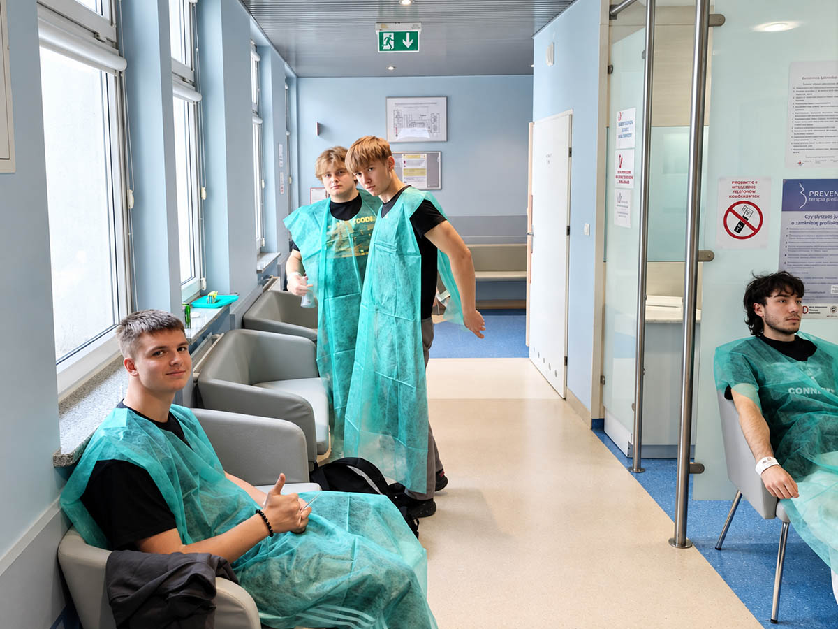 Uczestnicy akcji krwiodawstwa ZSŁ w zielonych fartuchach ochronnych na korytarzu punktu poboru krwi