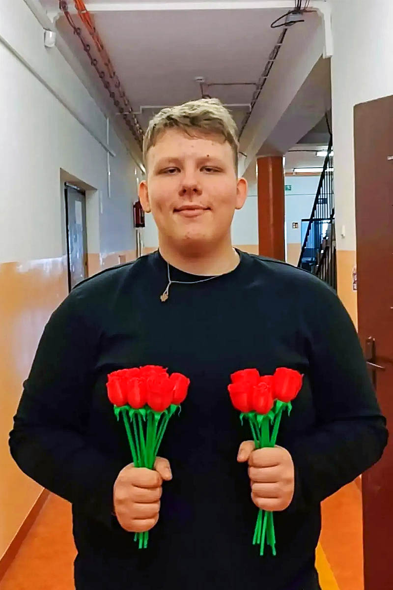 Mateusz Ładkowski, kandydat do Samorządu Uczniowskiego, trzymający czerwone kwiaty