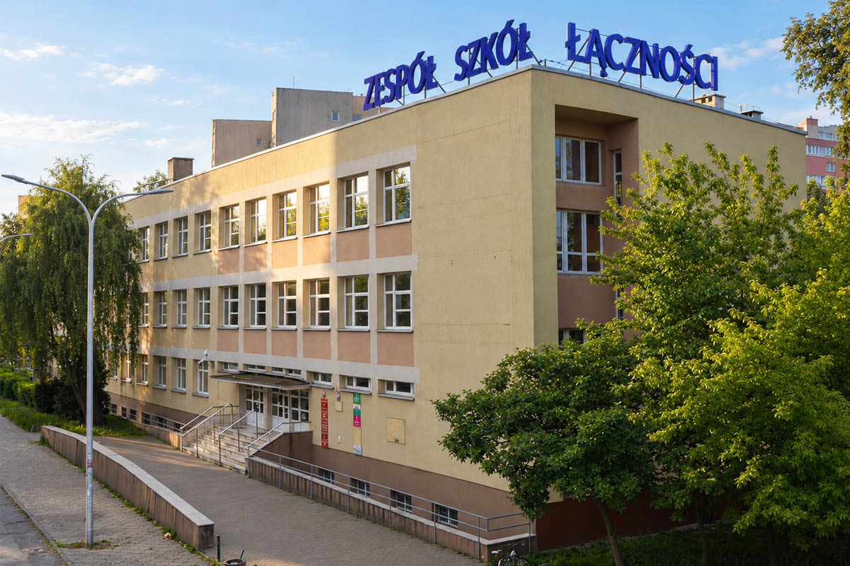 Budynek Zespołu Szkół Łączności w Warszawie widziany od strony wejścia, otoczony zielenią