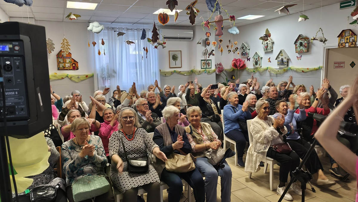 Seniorzy zgromadzeni na widowni podczas występu Teatru NORA w Dziennym Domu Pomocy Społecznej