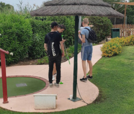 Uczniowie stoją przy kolejnym torze podczas gry w minigolfa.