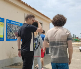 Uczniowie stoją przed wypożyczalnią sprzętu przed lekcją pływania kajakami.