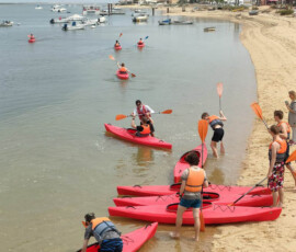 Grupa uczniów kończy lekcję pływania kajakami na plaży.