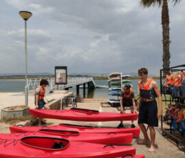 Uczestnicy mobilności przygotowują czerwone kajaki na plaży.