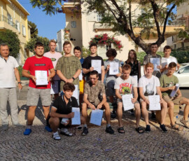 Druga grupa uczestników mobilności Erasmus+ w Faro pozuje z certyfikatami na tle miejskiej zabudowy.