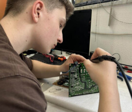 Uczeń wykonuje zadanie techniczne z urządzeniem elektronicznym podczas praktyk.