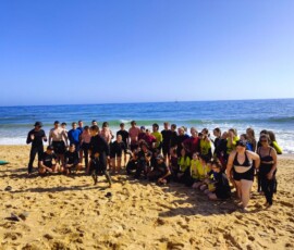 Uczestnicy Erasmus+ pozują na plaży z deskami surfingowymi przed zajęciami na Praia de Faro.