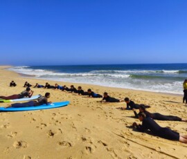 Deski surfingowe leżą w rzędzie na piasku podczas zajęć na Praia de Faro.