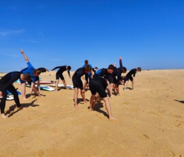 Grupa uczniów biegnie po plaży podczas rozgrzewki przed zajęciami.