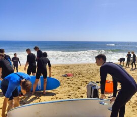 Uczniowie przygotowują deski i sprzęt surfingowy na plaży.