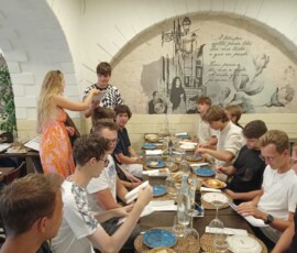 Uczniowie i opiekunowie jedzą wspólny posiłek podczas zakończenia mobilności Erasmus+.