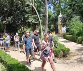 Uczniowie spacerują po zielonym parku podczas zwiedzania Sewilli.