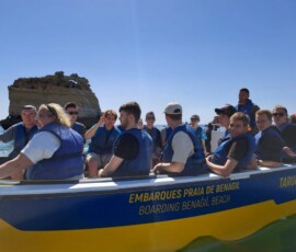 Grupa uczniów siedzi w żółtej łodzi podczas rejsu wzdłuż wybrzeża Algarve.