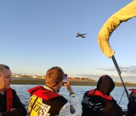 Uczestnicy Erasmus+ siedzą na pokładzie łodzi podczas zachodu słońca.