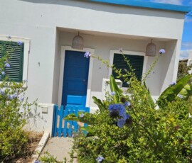 Biały dom z niebieskimi drzwiami otoczony ogrodem w Algarve.