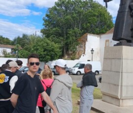 Uczniowie stoją przy wysokim pomniku podczas zwiedzania okolic Faro.