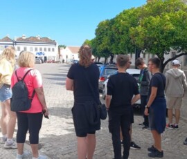 Grupa uczniów idzie przez słoneczny plac podczas czasu wolnego w Portugalii.