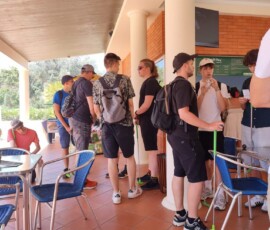 Uczniowie stoją przy stolikach w strefie odpoczynku obok pola minigolfa.