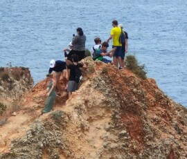 Grupa uczniów spaceruje po punkcie widokowym nad skalistym wybrzeżem Algarve.