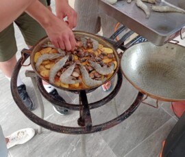 Uczniowie przygotowują potrawę na dużej patelni podczas warsztatów kulinarnych.