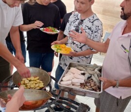 Uczniowie stoją wokół stanowiska kuchennego i przygotowują posiłek.