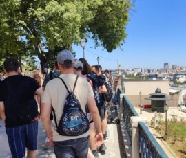 Uczestnicy mobilności odpoczywają pod drzewami podczas zwiedzania Lizbony.