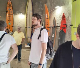 Uczestnik mobilności ogląda ekspozycję z deskami surfingowymi w Nazaré.