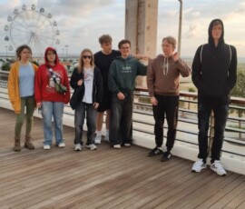 Grupa uczestników pozuje przy pomniku na nadmorskiej promenadzie w Figueira da Foz.