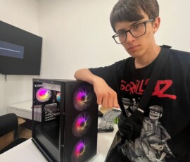 Uczeń pracuje przy komputerze stacjonarnym podczas praktyk w firmie technologicznej.