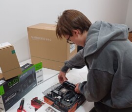 Uczniowie pracują przy podzespołach komputerowych podczas praktyk w firmie technologicznej.