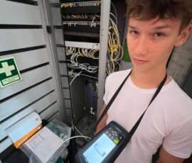 Uczeń wykonuje pomiary przy urządzeniu elektronicznym podczas pracy w firmie.