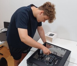 Uczeń pracuje nad otwartym komputerem stacjonarnym podczas zajęć w firmie.