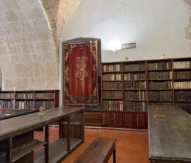 Zabytkowe wnętrze biblioteki z drewnianymi regałami oglądane przez uczestników.