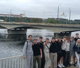 Grupa uczniów pozuje przy nabrzeżu podczas zwiedzania portugalskiego miasta.