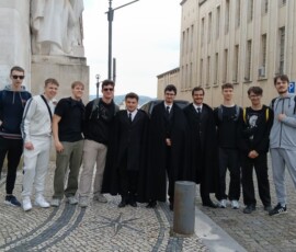 Uczniowie pozują przed monumentalnym zabytkowym budynkiem.