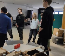 Uczniowie stoją przy wyposażeniu pracowni podczas zwiedzania szkoły partnerskiej.