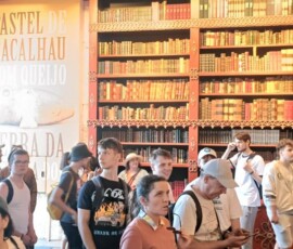 Uczniowie zwiedzają wnętrze z wysokimi regałami książek podczas pobytu w Porto.
