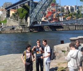 Uczniowie pozują nad Douro z mostem Dom Luís I w tle podczas wycieczki do Porto.