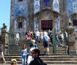 Uczestnicy stoją przed kościołem ozdobionym niebiesko-białymi płytkami azulejo w Porto.