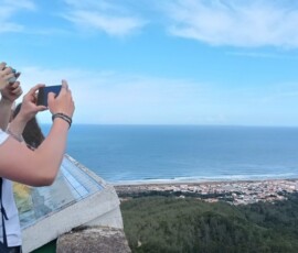 Uczennica fotografuje widok na ocean z wysokiego punktu widokowego.