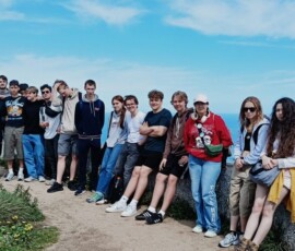 Uczestnicy Erasmus+ pozują do wspólnego zdjęcia na klifie nad oceanem.
