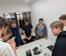 Uczniowie obserwują montaż podzespołów komputerowych na stole.