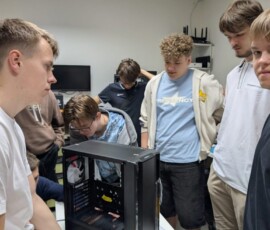 Uczniowie pracują przy otwartej obudowie komputera podczas zajęć technicznych.