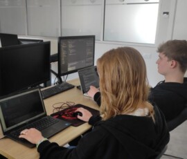 Dwoje uczniów pracuje wspólnie przy stanowisku komputerowym.