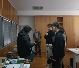 Uczniowie pracują przy stołach i urządzeniach podczas praktyk zawodowych w portugalskiej firmie.