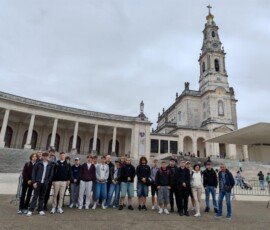 Uczniowie pozują w grupie na tle sanktuarium w Fatimie.