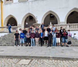 Uczestnicy Erasmus+ stoją razem na tle jasnej zabudowy w Sintrze.
